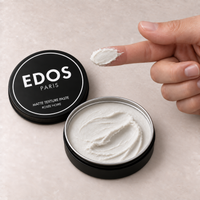 Matte Texture Paste EDOS Paris, dose de cire blanc cassé neutre étalée sur l’index près du pot ouvert.
